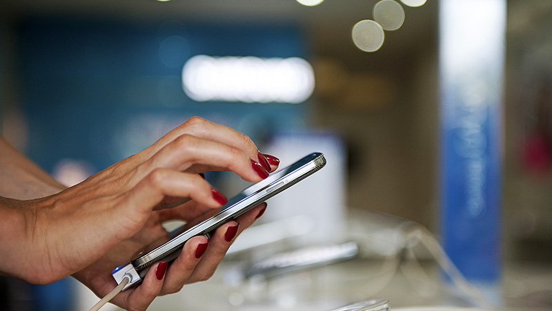 A closeup of a hand holding and interacting with a smart phone. A closeup of a hand holding and interacting with a smart phone.