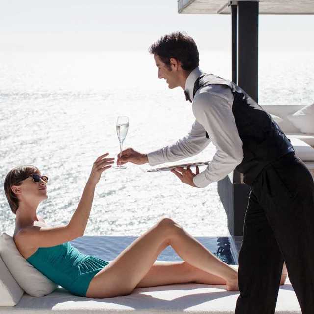 woman being served a drink by the ocean