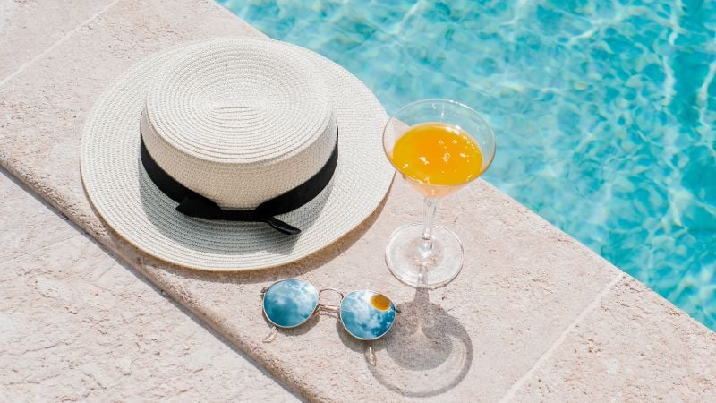 hat and drink by the pool